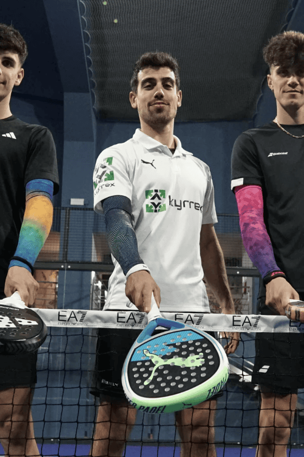 Three padel players standing at net wearing Floky No Strain Fusion compression arm sleeves in blue-orange and purple-pink gradient patterns, padel court lifestyle photo