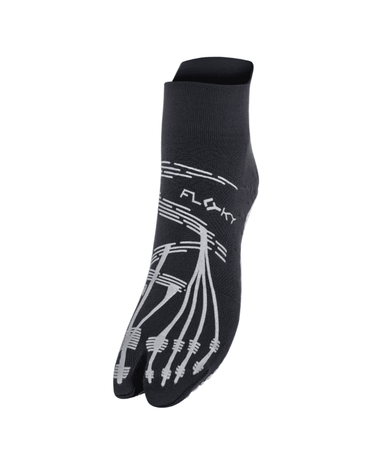 Angled side view of black Floky KINETICA Silver Metallic pilates grip sock showing silver FLOKY logo, anatomical toe-line grip pattern and split-toe design, product shot on white background