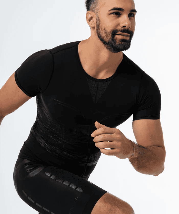 Male athlete in squat sprint start position wearing black Floky OXY-GEN short sleeve compression jersey and black compression shorts, upper body angled forward with arms bent, studio lifestyle action shot on white background