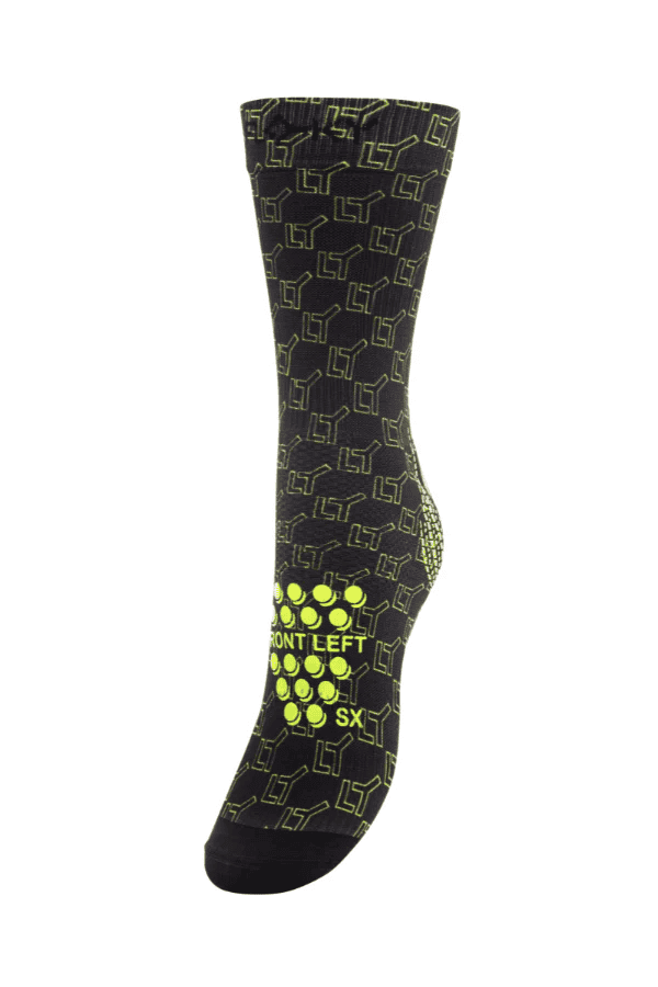 Floky S-Mash Logomania sock in black with neon yellow-green geometric cube logo pattern, sole view showing left foot label and grip dots, product shot on white background